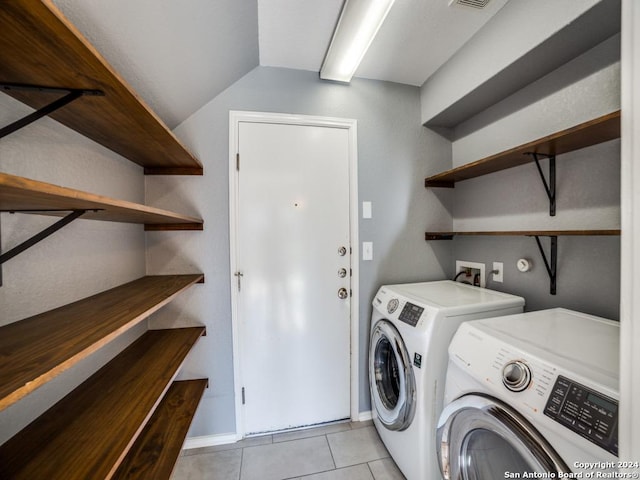 clothes washing area featuring light tile patterned floors and washer and dryer