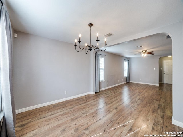 spare room featuring light wood-type flooring and ceiling fan with notable chandelier