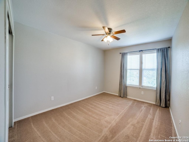 empty room with ceiling fan and light colored carpet