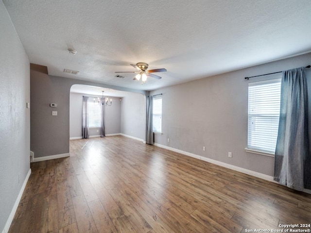 spare room featuring ceiling fan with notable chandelier, a wealth of natural light, and hardwood / wood-style floors