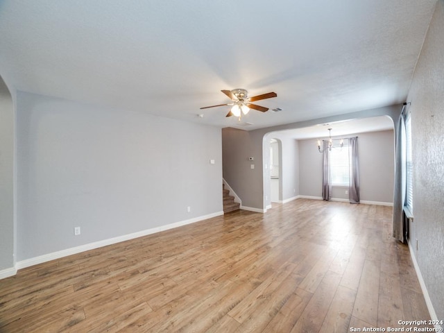 spare room featuring ceiling fan with notable chandelier and light hardwood / wood-style flooring