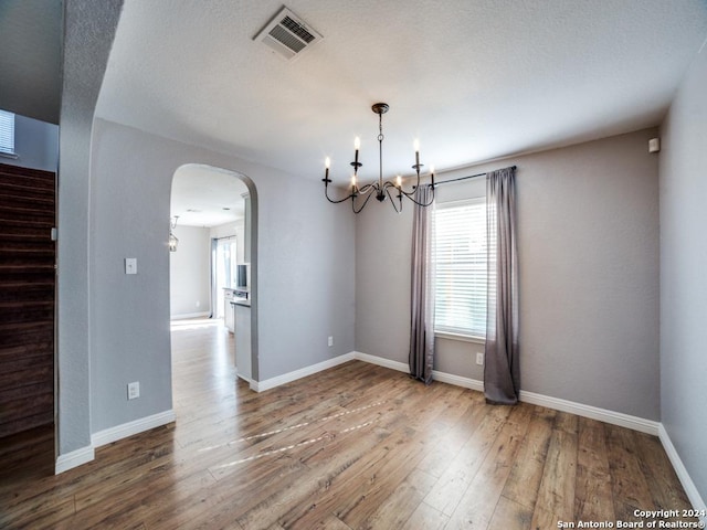 empty room featuring a chandelier and hardwood / wood-style floors