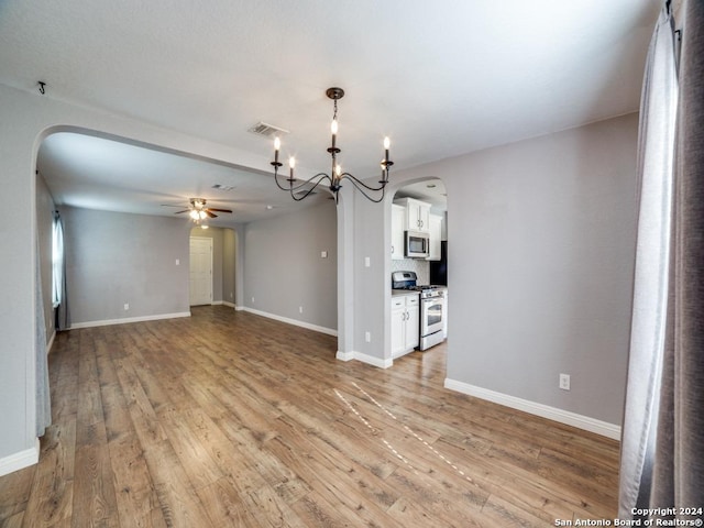 unfurnished living room featuring light wood-type flooring and ceiling fan with notable chandelier