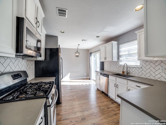 kitchen featuring decorative light fixtures, sink, stainless steel appliances, and white cabinetry