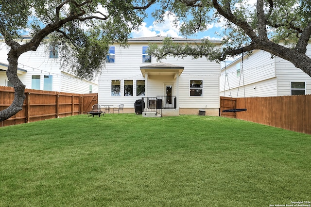 back of house with a fire pit and a lawn