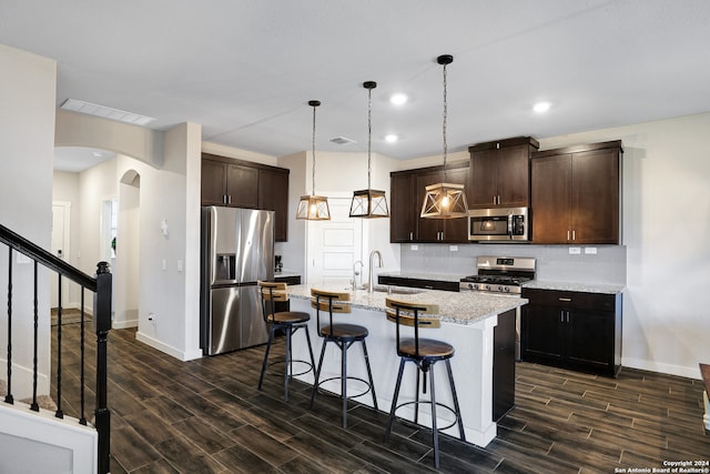 kitchen featuring dark brown cabinetry, stainless steel appliances, an island with sink, and sink