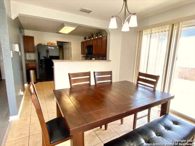 tiled dining room featuring an inviting chandelier