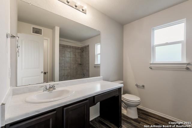 bathroom featuring a wealth of natural light, vanity, wood-type flooring, and toilet