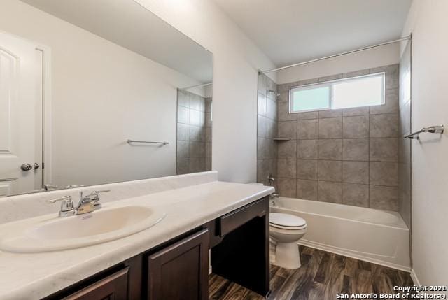 full bathroom with hardwood / wood-style flooring, toilet, vanity, and tiled shower / bath