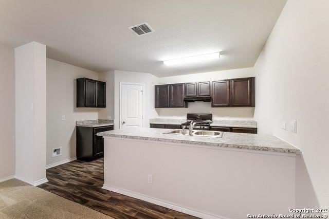 kitchen featuring range, dark brown cabinetry, dark hardwood / wood-style floors, and sink