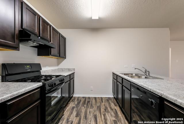 kitchen with dark hardwood / wood-style flooring, dark brown cabinets, a textured ceiling, sink, and black appliances