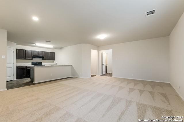 kitchen featuring black range oven, light colored carpet, and dark brown cabinetry