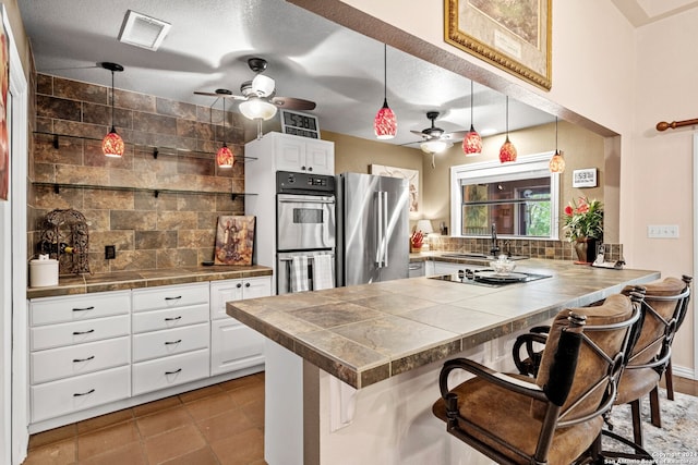 kitchen featuring white cabinetry, ceiling fan, hanging light fixtures, a breakfast bar, and appliances with stainless steel finishes