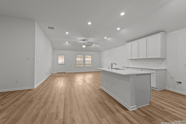 kitchen with sink, light hardwood / wood-style flooring, ceiling fan, a kitchen island with sink, and white cabinets