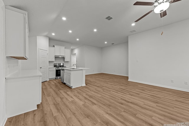 kitchen with ceiling fan, stainless steel range, an island with sink, white cabinets, and light wood-type flooring