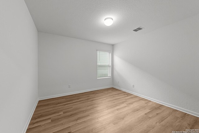 empty room with a textured ceiling and light wood-type flooring