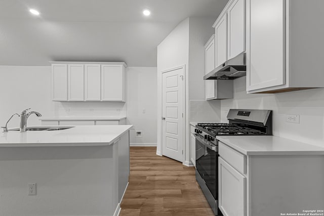 kitchen with sink, white cabinets, decorative backsplash, gas range, and light wood-type flooring