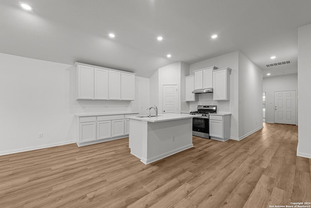 kitchen with sink, stainless steel stove, a center island with sink, and white cabinets