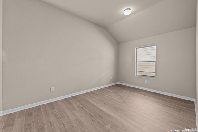 spare room with lofted ceiling and light wood-type flooring