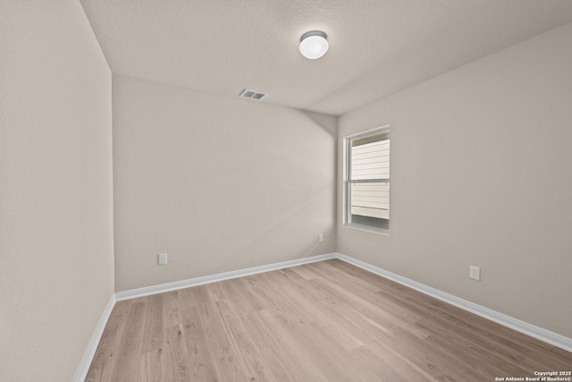 empty room featuring light wood-type flooring and a textured ceiling