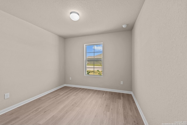 spare room with light wood-type flooring and a textured ceiling