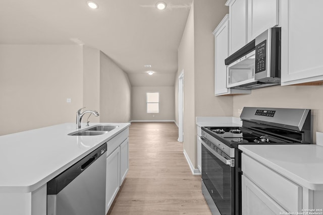 kitchen featuring sink, stainless steel appliances, white cabinetry, and a center island with sink