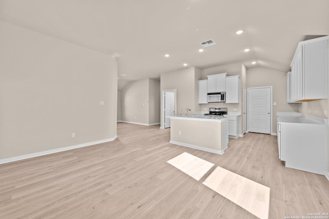 kitchen with light hardwood / wood-style floors, stainless steel stove, white cabinets, and a kitchen island with sink