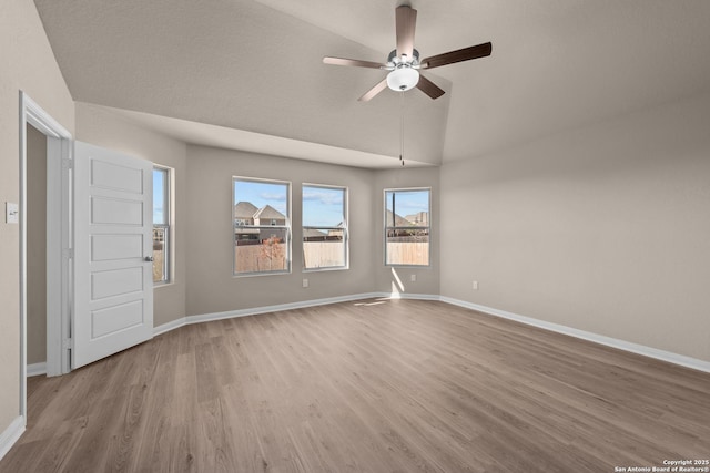 empty room with lofted ceiling, light hardwood / wood-style flooring, and ceiling fan