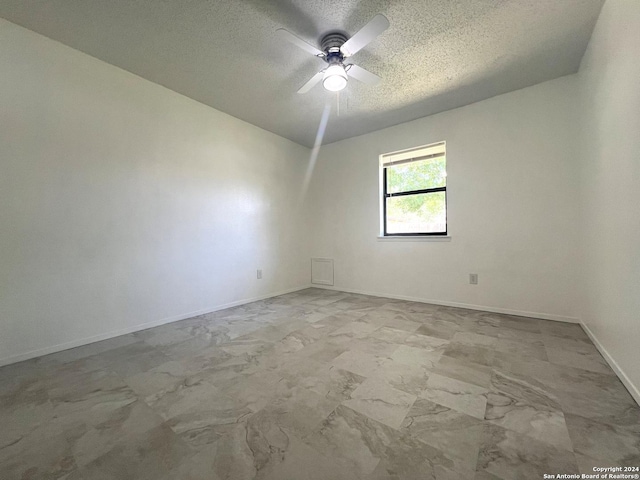 empty room with ceiling fan and a textured ceiling