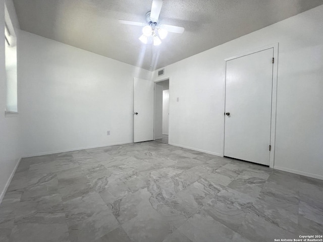 spare room with a textured ceiling and ceiling fan