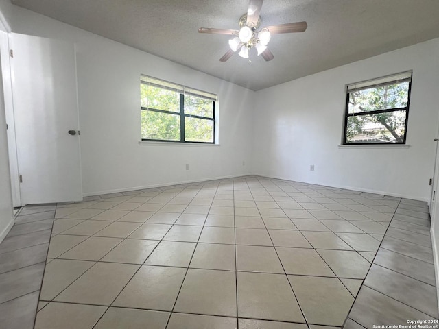 empty room with light tile patterned flooring, ceiling fan, and a textured ceiling