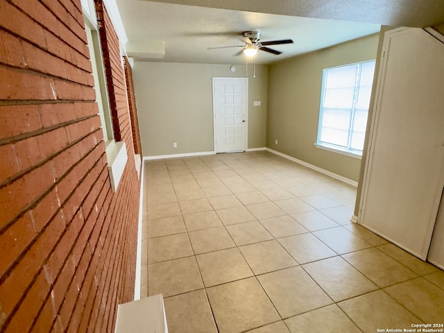 empty room with a textured ceiling, ceiling fan, and light tile patterned floors