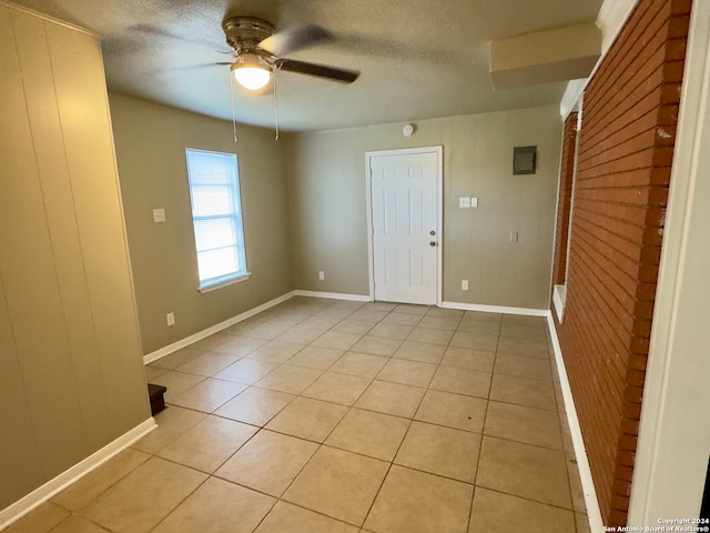 tiled spare room featuring a textured ceiling and ceiling fan