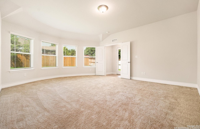 unfurnished room featuring plenty of natural light, light colored carpet, and lofted ceiling