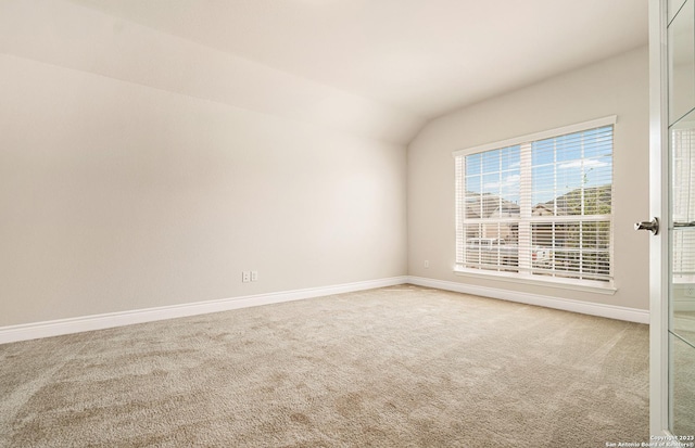 carpeted empty room with lofted ceiling