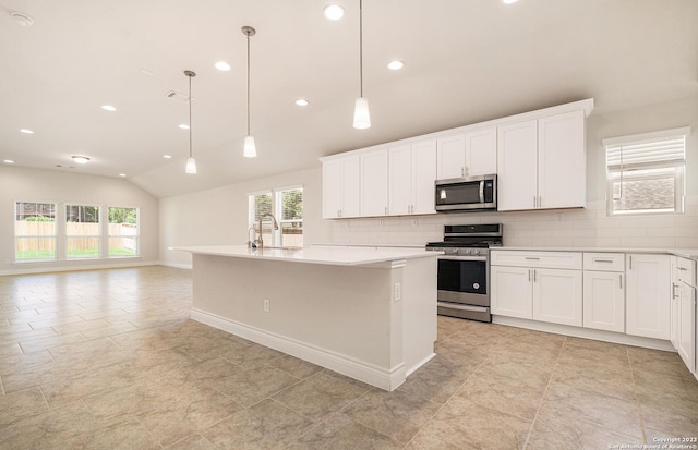 kitchen with hanging light fixtures, stainless steel appliances, an island with sink, and vaulted ceiling