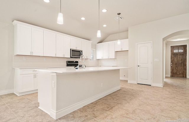 kitchen featuring white cabinetry, decorative backsplash, a kitchen island with sink, and pendant lighting