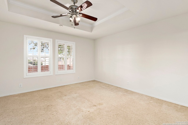 carpeted empty room with ceiling fan, crown molding, and a tray ceiling