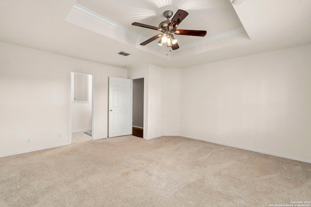 carpeted empty room with ceiling fan and a tray ceiling