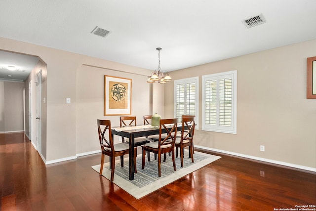 dining room with dark hardwood / wood-style floors and an inviting chandelier