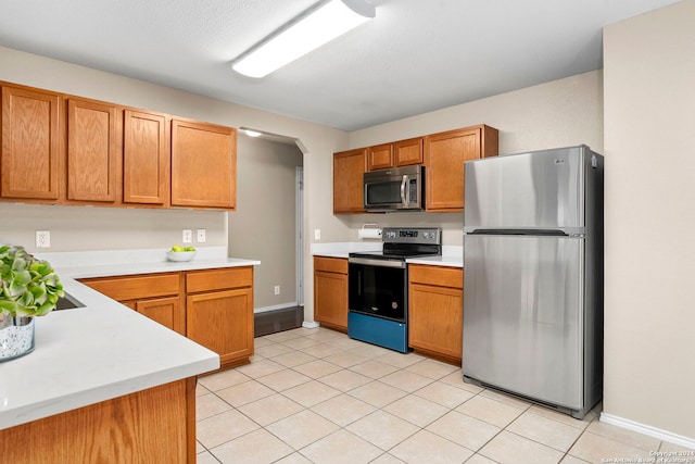 kitchen featuring light tile patterned floors, a textured ceiling, and appliances with stainless steel finishes