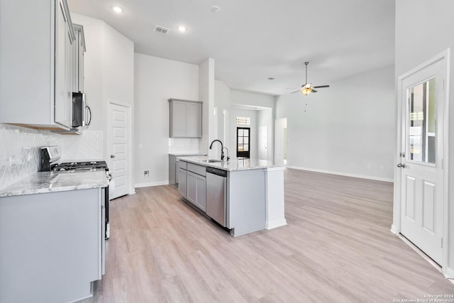 kitchen with gray cabinetry, ceiling fan, light stone countertops, light wood-type flooring, and stainless steel appliances