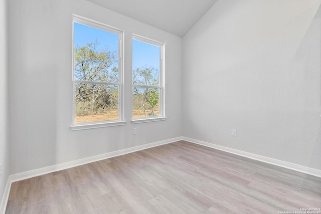 empty room featuring lofted ceiling and light hardwood / wood-style flooring