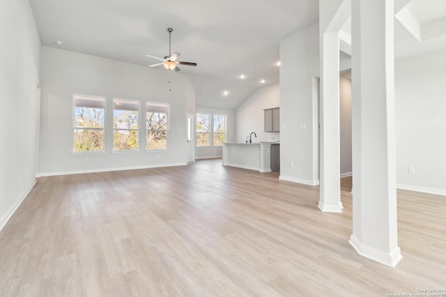 unfurnished living room featuring ceiling fan, light wood-type flooring, sink, and lofted ceiling