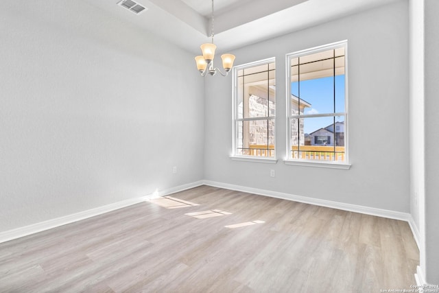 empty room featuring light wood-type flooring and a chandelier