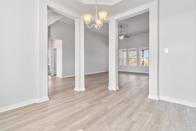 unfurnished dining area with ceiling fan with notable chandelier and light hardwood / wood-style flooring