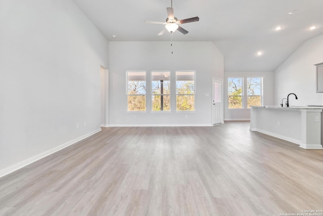 unfurnished living room with ceiling fan, lofted ceiling, sink, and light hardwood / wood-style flooring