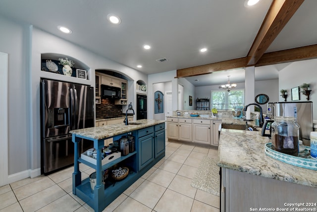 kitchen with stainless steel refrigerator with ice dispenser, light stone countertops, sink, decorative backsplash, and a center island with sink