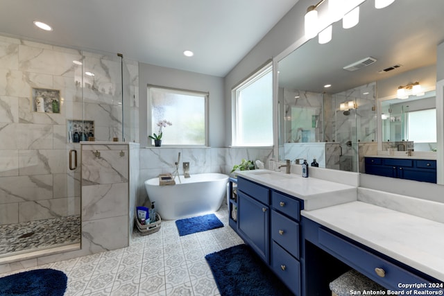 bathroom featuring shower with separate bathtub, vanity, tile walls, and tile patterned floors