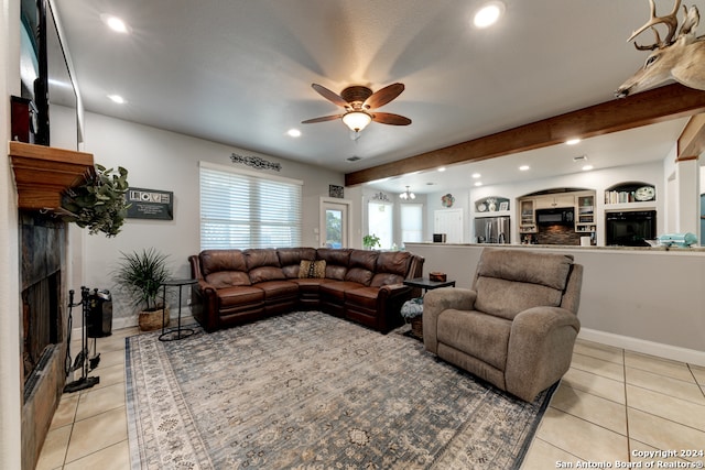 tiled living room with beam ceiling, built in features, a high end fireplace, and ceiling fan